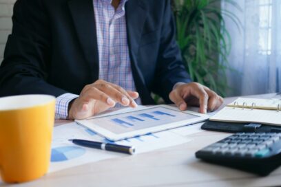 Man with a calculator and iPad with graphs