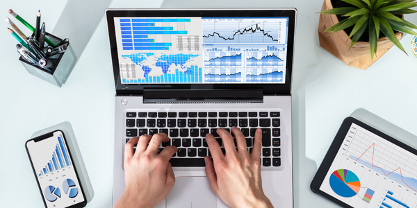 человек с ноутбуком сидит за столом, на экране график роста продаж