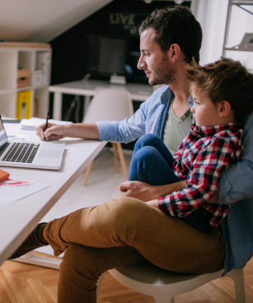 A picture of Eli working from home with his son on his lap