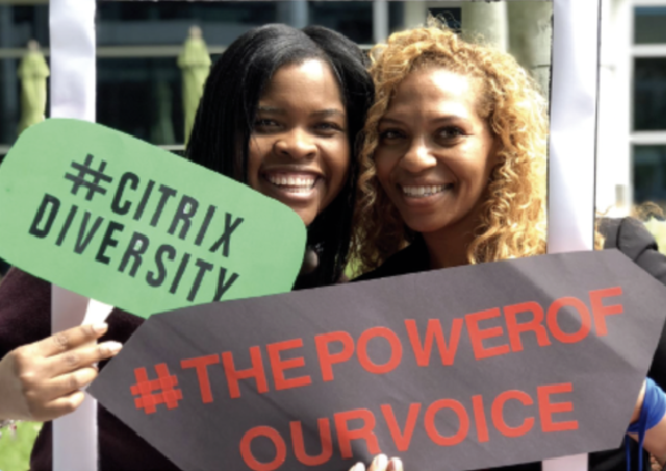 Two Citrix team members holding signs reading #CitrixDiversity and #ThePowerOfOurVoice