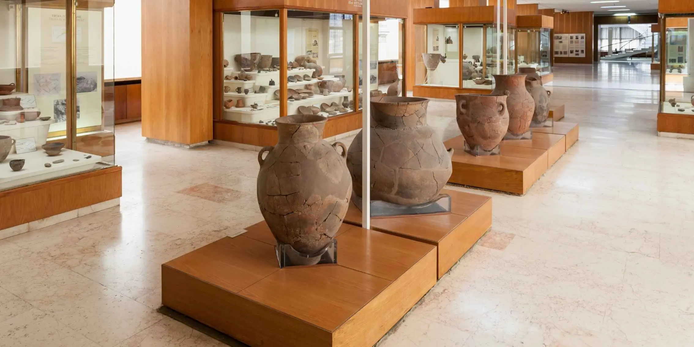 Interior of a museum displaying large reconstructed ceramic amphorae and
        pottery artifacts in glass cases