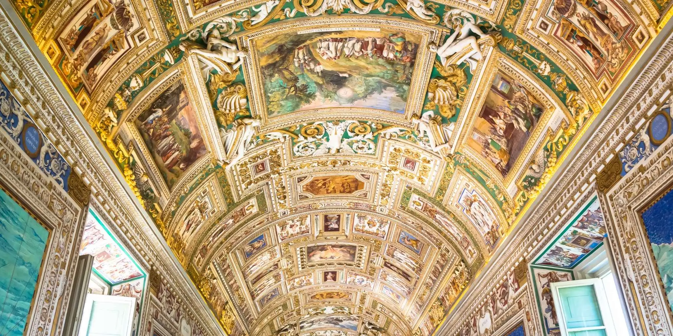 Ornately decorated ceiling of a classical European gallery with gilded
        architectural details and Renaissance-style frescoes