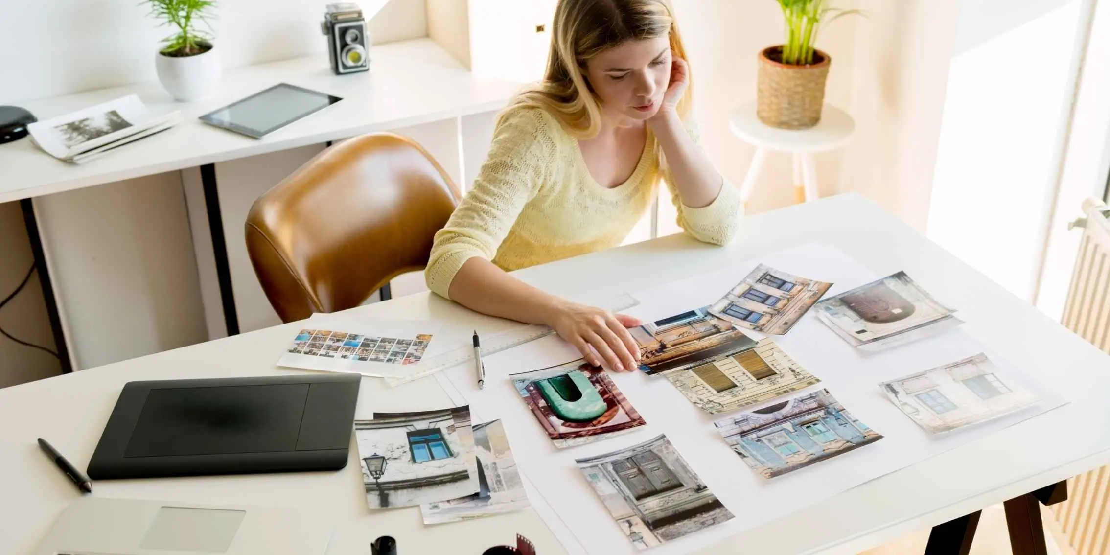 Curator or designer reviewing printed architectural photographs at a
            bright, modern desk