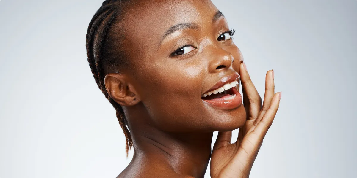 Portrait of happy black woman in studio with cosmetics
