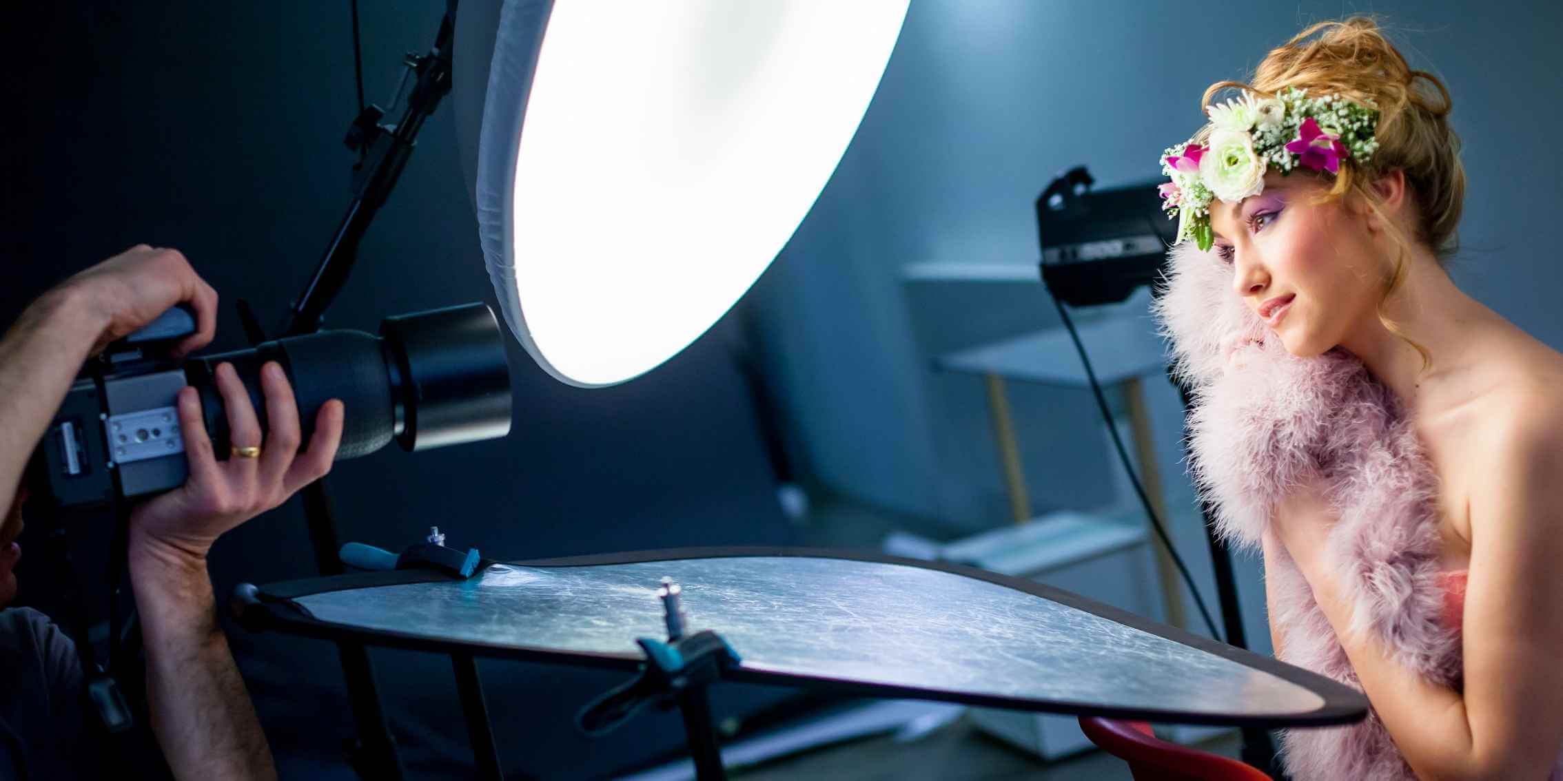 View of a photographer’s hands capturing a portrait image in a
studio, with a female subject wearing a flower headpiece