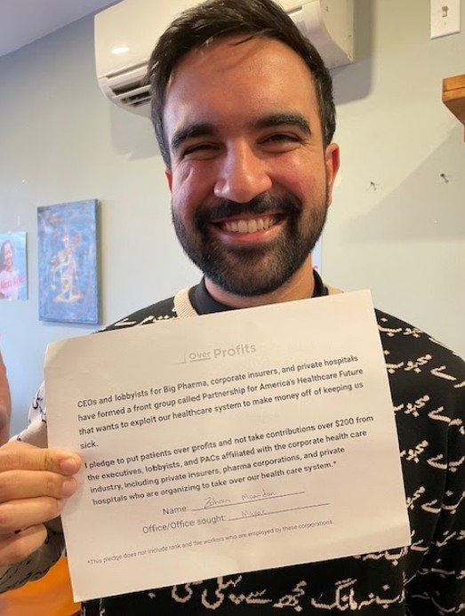 Photo of Zohran Mamdani holding the signed Patients Over Profits pledge