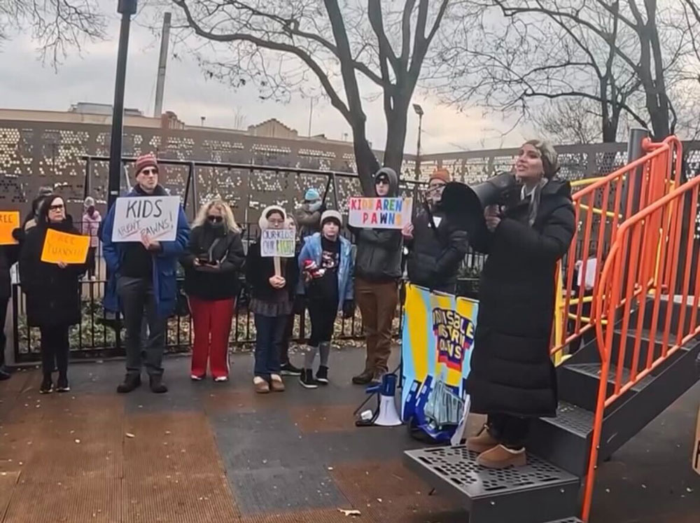 A speaker stands on a jungle gym holding a megaphone at a rally in New York City