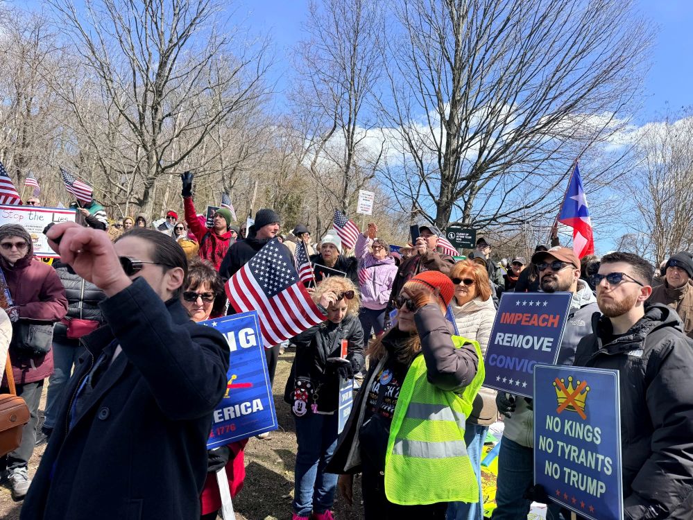 A group of people marching with American flags and signs that read IMPEACH REMOVE CONVICT and NO KINGS NO TYRANTS NO TRUMP