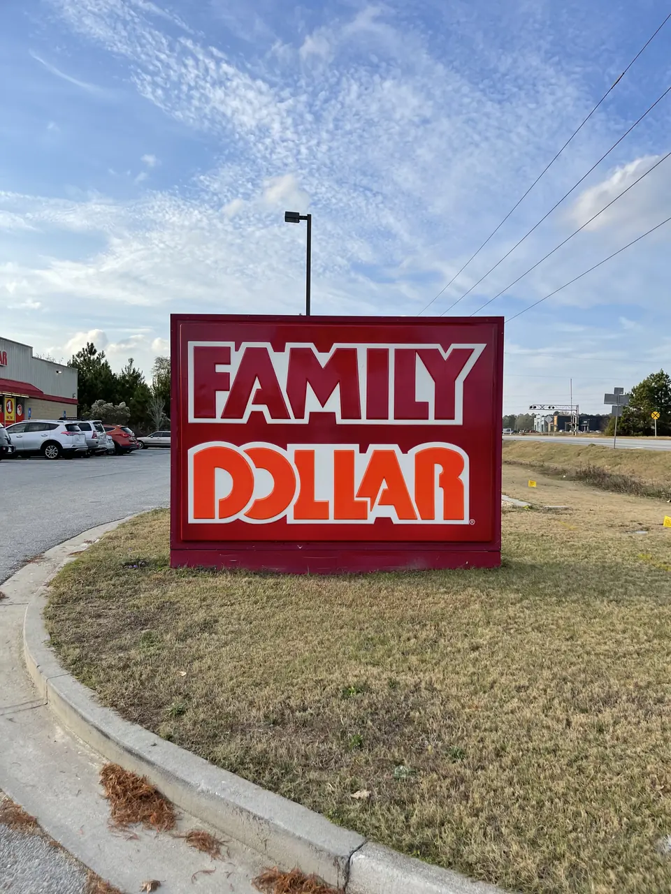 Family Dollar cabinet monument sign at street level near the entry drive.