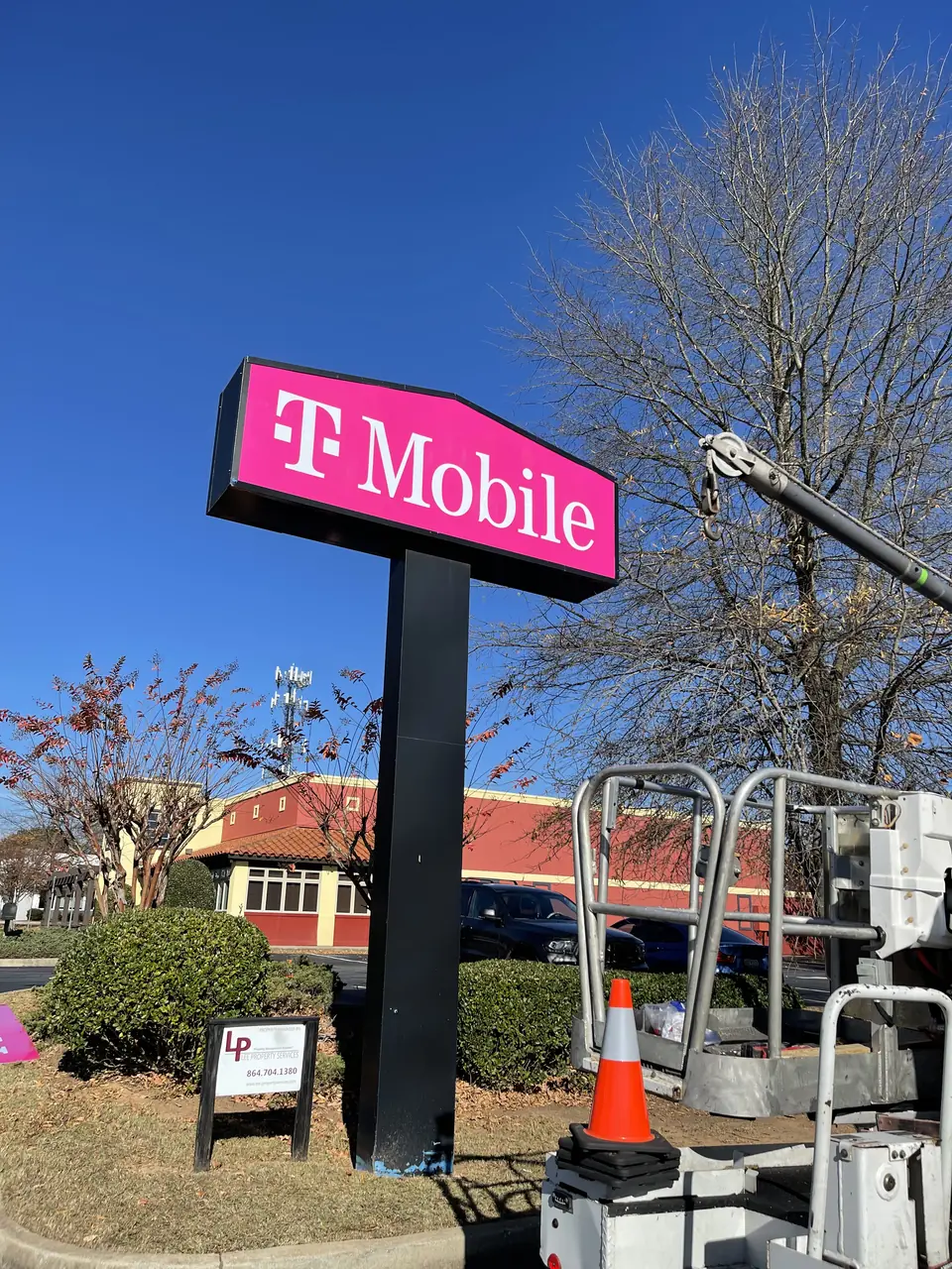 T‑Mobile large pole‑mounted illuminated cabinet sign above the roadside.