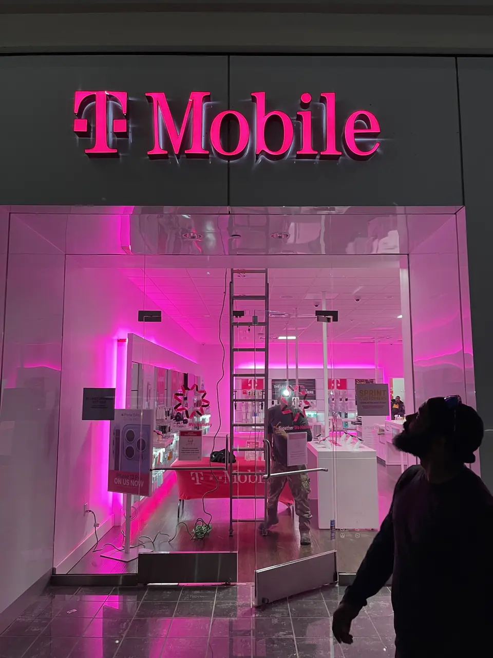 T‑Mobile storefront with bright pink illuminated letters above the entrance.