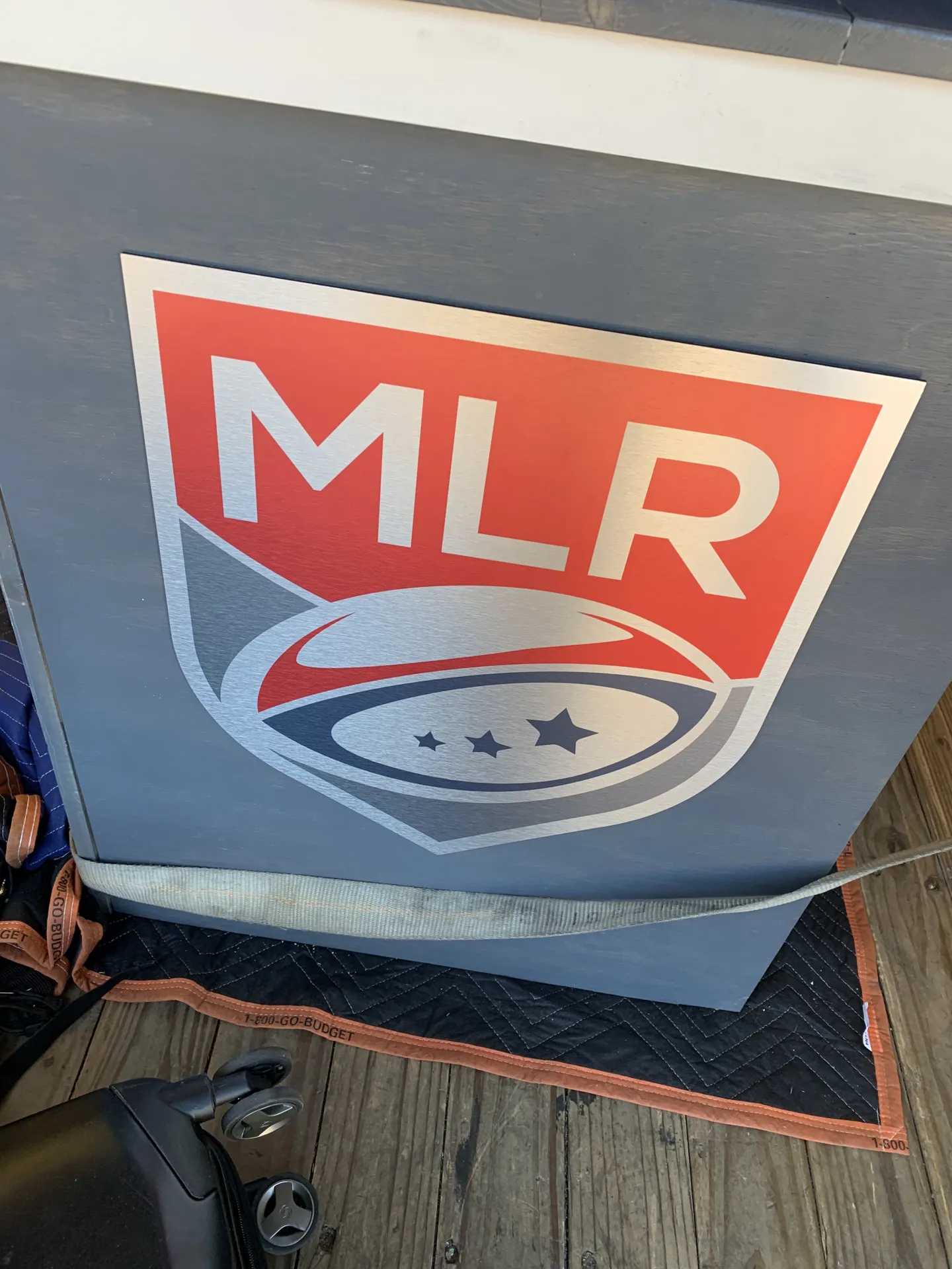 Small logo sign applied to the side of the desk, demonstrating secondary branding placement and finish alignment.