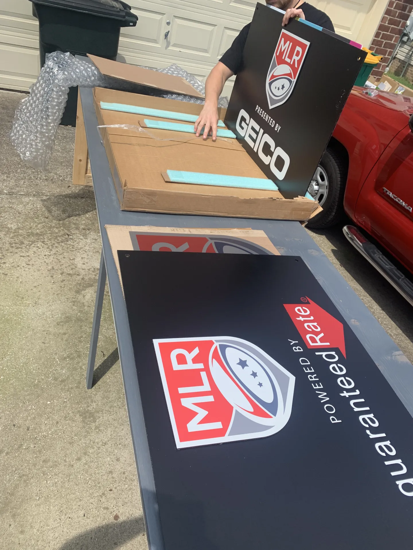 Black MLR sign with logo for front of desk, staged before installation with clean edges and sponsor space reserved.