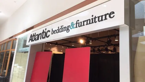 White Atlantic Bedding and Furniture store sign above storefront with bright letters against a dark background.