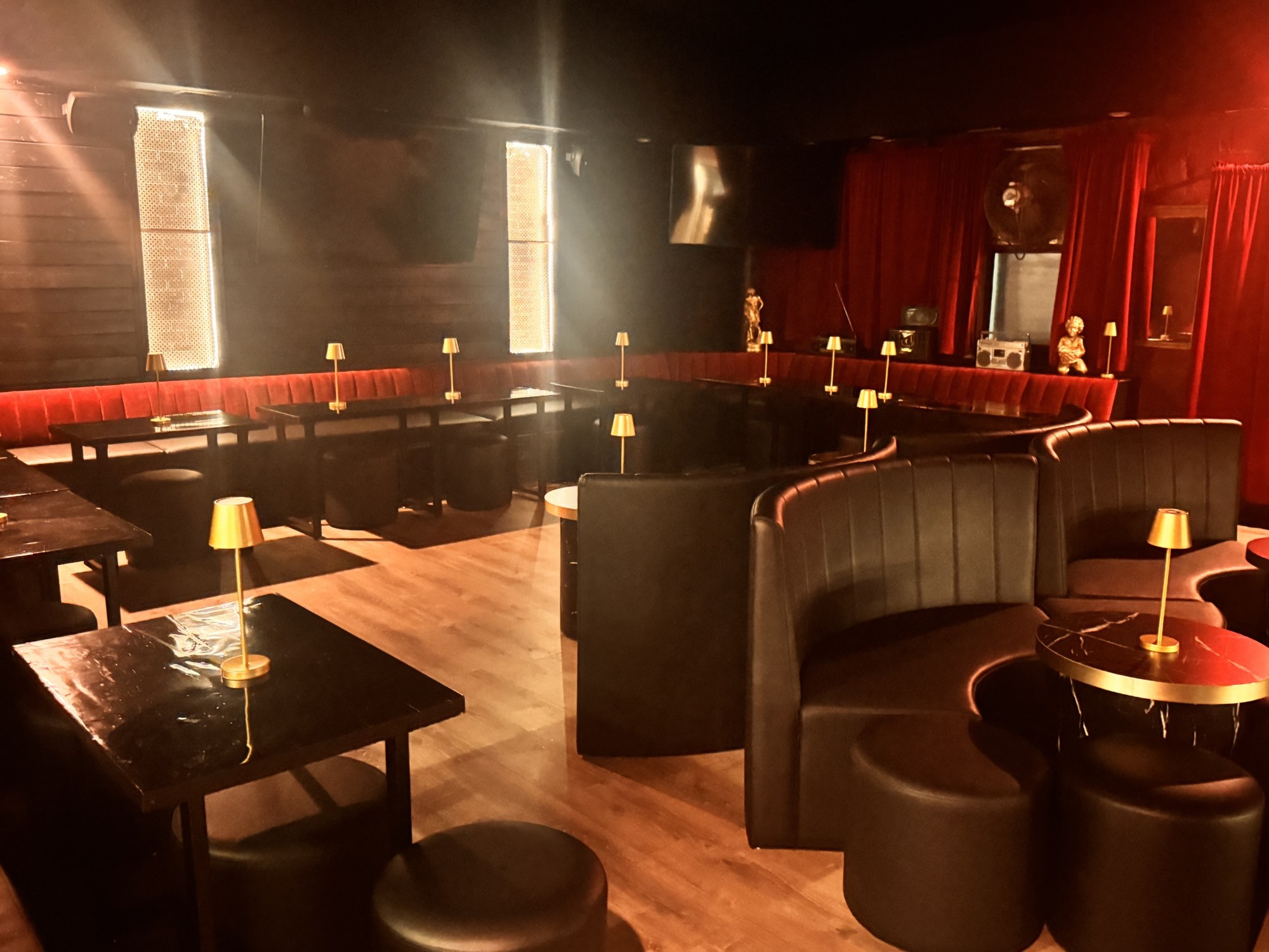 Long velvet banquette and curved leather booths under brass lamps
