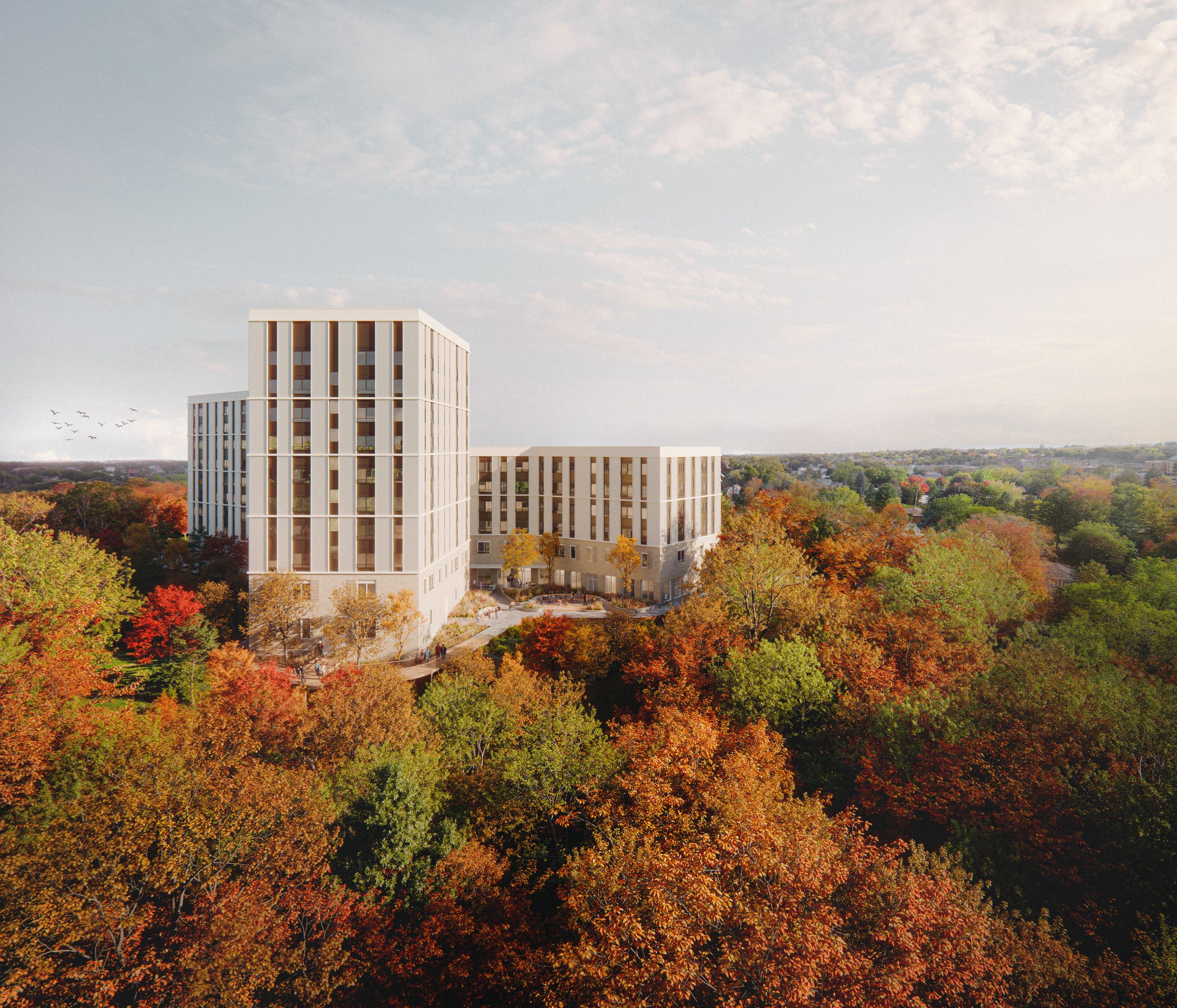 Modern residential towers situated among vibrant autumn foliage in an urban parkland setting.