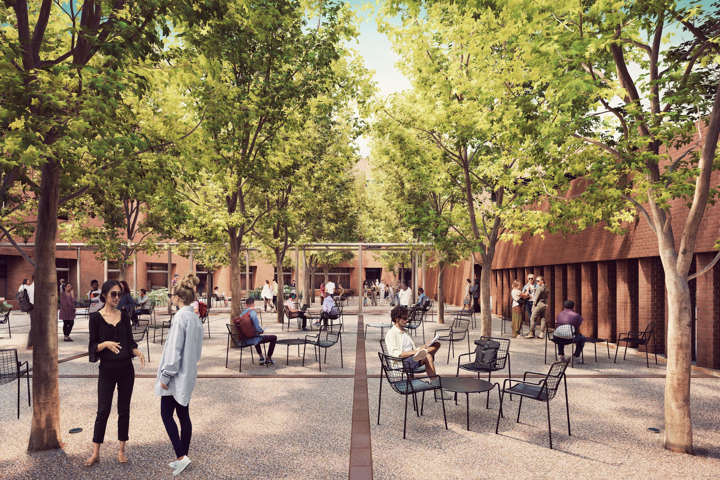 Outdoor campus courtyard with shaded seating area featuring scattered chairs beneath mature trees and brick buildings.