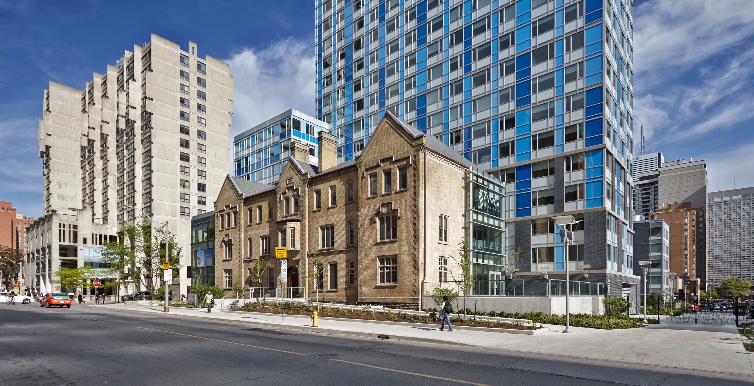 Urban streetscape showing architectural contrast between historic brownstone buildings and modern glass high-rise towers.
