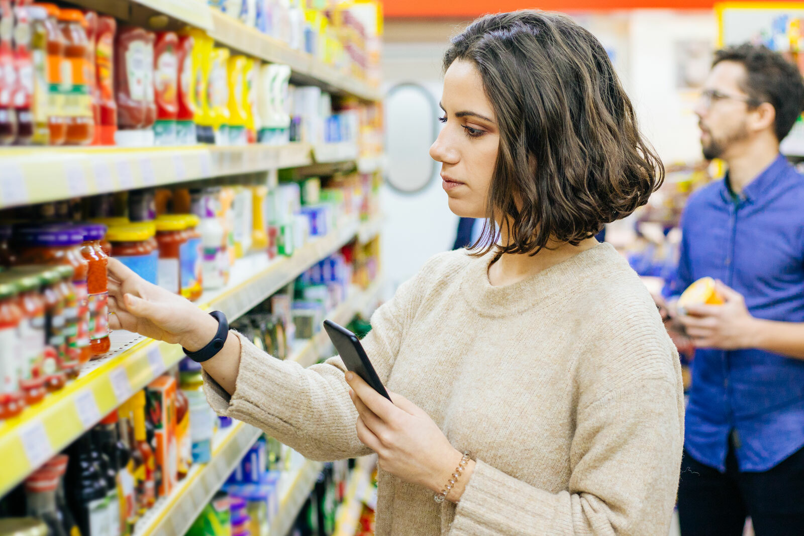 Woman shopping grocery store aisle and comparing products
