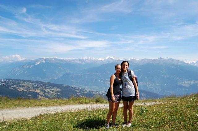 Teenage travelers hike through Swiss Alps on summer youth adventure travel program