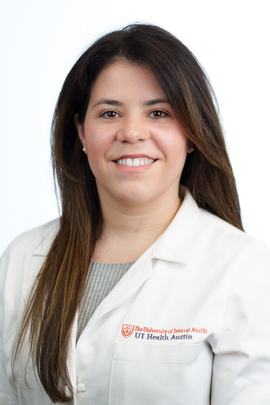 Marivee Borges is smiling at the camera. She is wearing a grey blouse and a white coat.